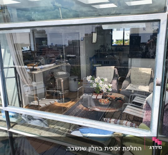 חלון זכוכית גדול עם השתקפות של חדר פנימי